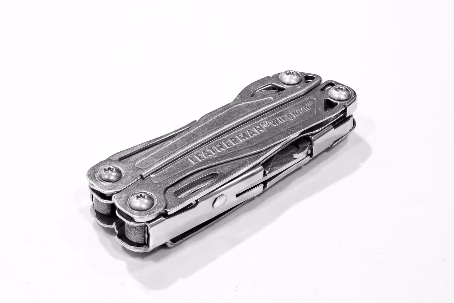 A Leatherman brand multi-tool, handles folded closed, showing pliers head and tool hinges.